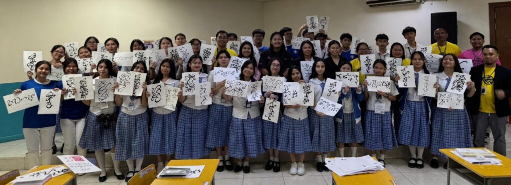 Group of Filipino students and teachers proudly holding Baybayin writing sheets in a classroom, promoting Philippine cultural heritage and indigenous script revival.